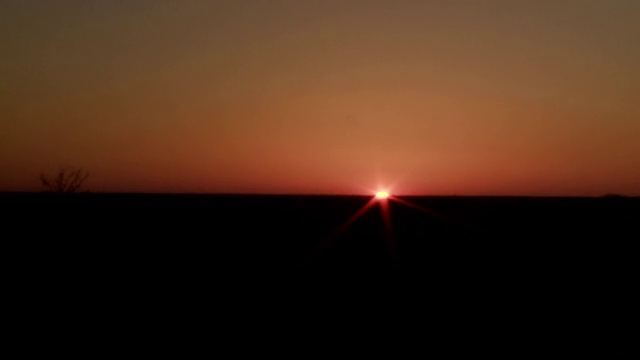 太阳消失在黑暗平坦的地平线后面。视频素材