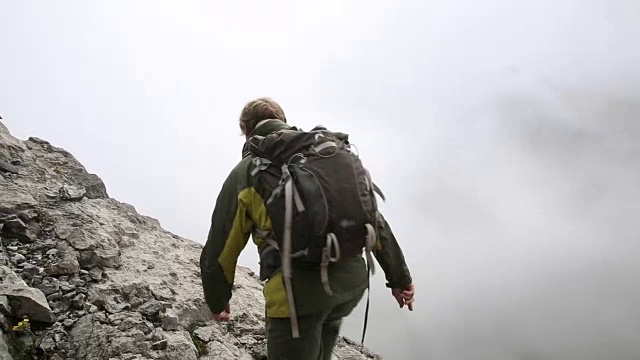 男徒步者攀登山脊，上面的山，薄雾视频素材