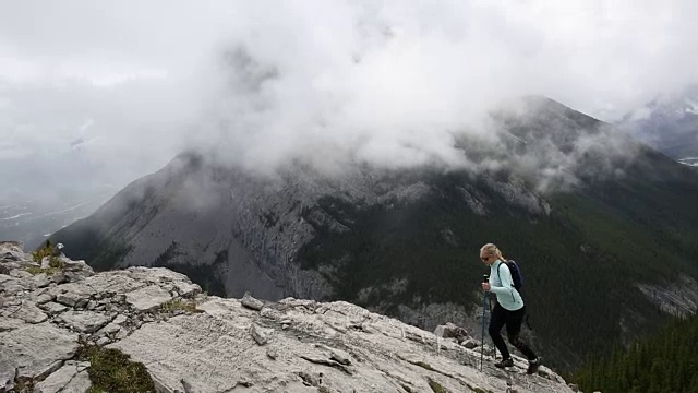 女性徒步旅行者攀登山脊之上的薄雾山谷，山脉视频素材