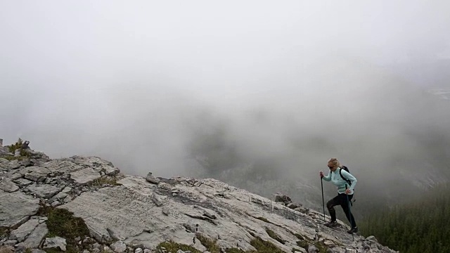 女性徒步旅行者攀登山脊之上的薄雾山谷，山脉视频素材