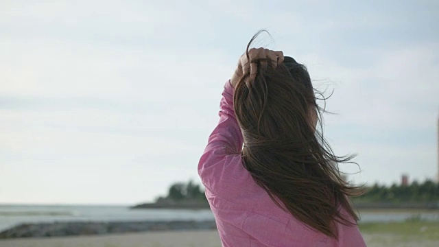 年轻的日本女性站在那里望着大海。视频素材