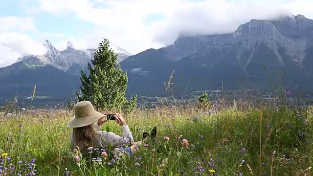 女人在草地上放松，望着远处的山脉和森林视频素材