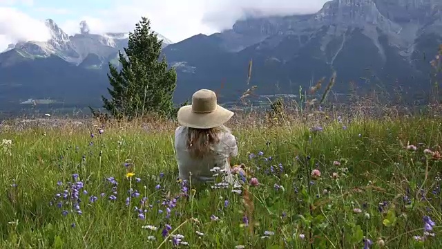 女人在草地上放松，望着远处的山脉和森林视频素材