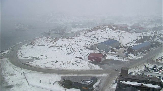 浓雾笼罩着一个下雪的沿海城镇。视频素材