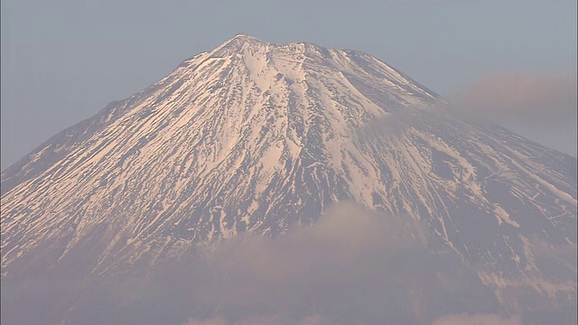 富士山隐现在一列火车上，火车正在田野里的一座桥上行驶。视频素材