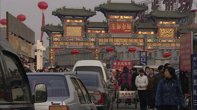 在为庆祝中国新年而装饰的街道上，行人走在车流前面。视频素材