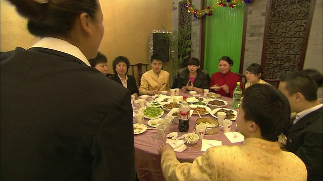 餐桌旁的食客们用装饰好的纸杯敬酒庆祝中国新年。视频素材