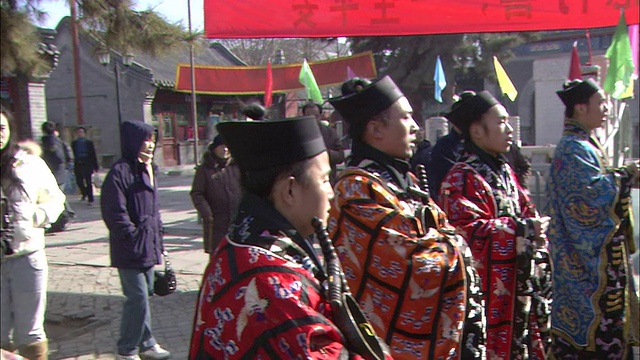 在中国北京的一个节日上，穿着传统服装的男子在一个拿着丝带棒的男子旁边摇铃。视频素材