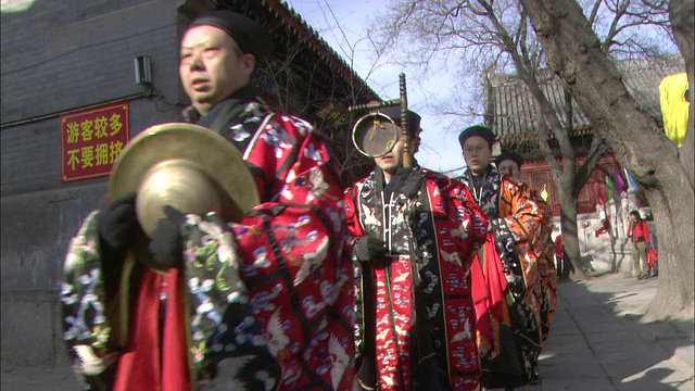 在中国北京的一个节日上，身着传统服装的男子在展示乐器。视频素材