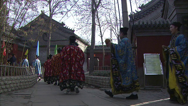 在中国北京，穿着传统服装的音乐家们走过带有中国建筑风格的建筑。视频素材