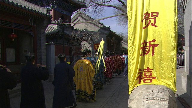 在中国北京，一群穿着传统服装的男子走过一条写有汉字的横幅。视频素材