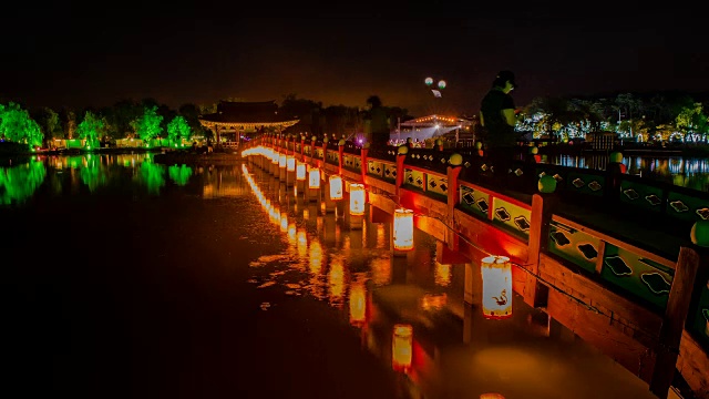 人们带着纸灯笼桥在夜晚穿越Gungnamji池塘(韩国135历史遗址，韩国第一个人工池塘，由Baekje王朝的穆王创造)的延时镜头视频素材