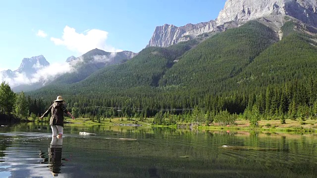 女人涉水穿过山湖到岩石岛视频素材