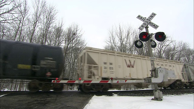 雪落在经过铁路道口的火车上。视频素材