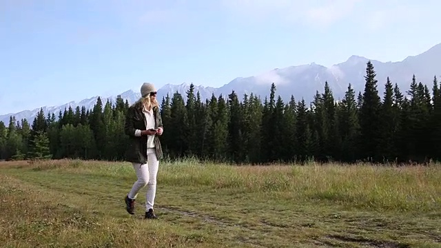 女人沿着小径穿过草地，身后是连绵的山脉视频素材