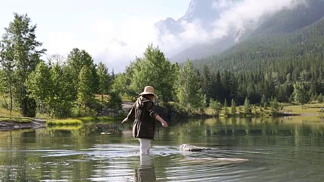 女人涉水穿过山湖到岩石岛视频素材