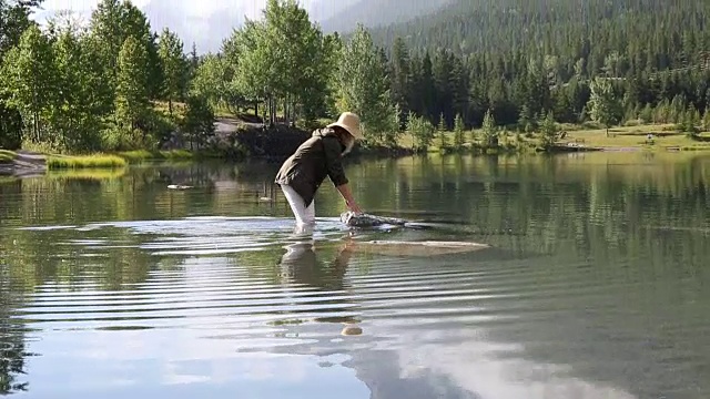 女人涉水穿过山湖到岩石岛视频素材