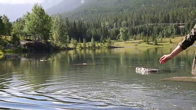 女人涉水穿过山湖到岩石岛视频素材