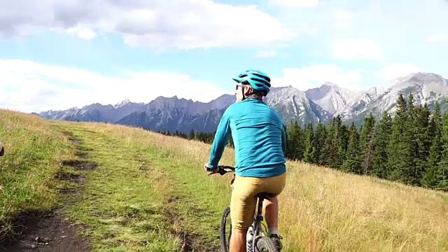 一对夫妇骑着自行车穿过草地，上面是山视频素材