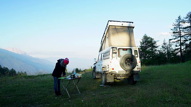 女人露营准备晚餐旁边4x4露营车视频素材