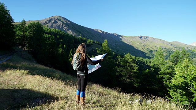 女性徒步旅行者看地图和山的观点视频素材