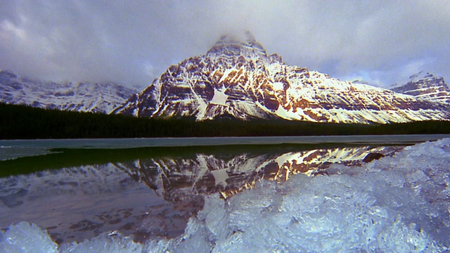 湖上的冰/雪山+时间流逝的云在背景+反射在湖/加拿大的后方视角视频素材