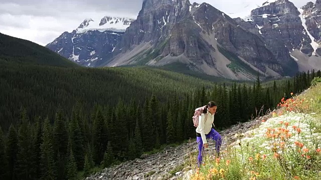 女性徒步旅行者爬上山坡，眺望群山和森林视频素材