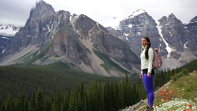 女性徒步旅行者爬上山坡，眺望群山和森林视频素材