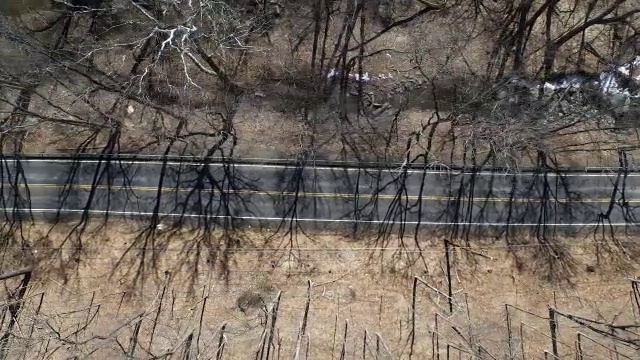 航拍直视下的乡村道路，旁边有一辆汽车和一条河视频素材