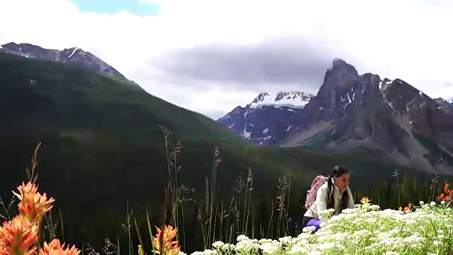 女性徒步旅行者爬上山坡，眺望群山和森林视频素材