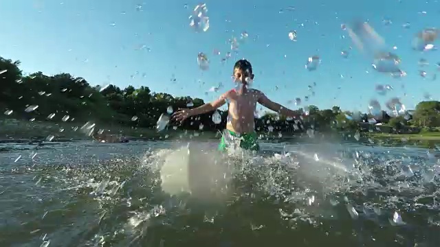 快乐的孩子们在湖边戏水，与闪闪发光的夕阳形成对比。视频素材