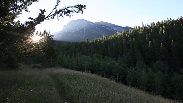 山地自行车穿过草地，太阳从后面的山上升起视频素材