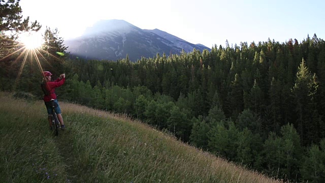 山地自行车沿着草地的路径，用智能手机拍照视频素材