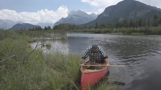 一名男子在山湖上划着木舟视频素材