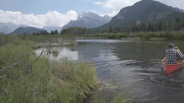 一名男子划着木独木舟进入山中湖泊视频素材