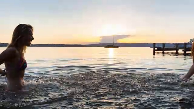 两名年轻女子在湖中泼水享受夏天视频素材