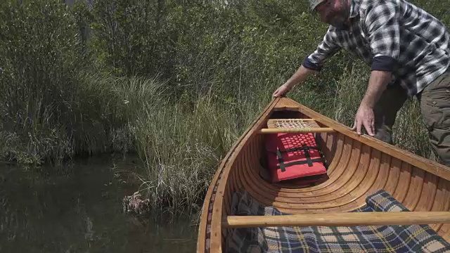 一名男子划着木独木舟进入山中湖泊视频素材