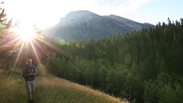 徒步旅行者沿着小径穿过草地，眺望高山和森林视频素材