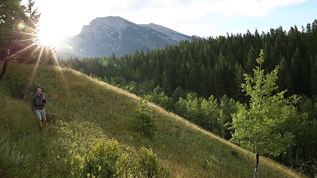 徒步者沿着草地山脊散步，眺望高山和森林视频素材