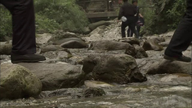 中国峨眉山，人们踏着石头过河视频素材