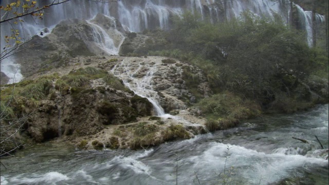 中国九寨沟，森林中的瀑布流入河流视频素材