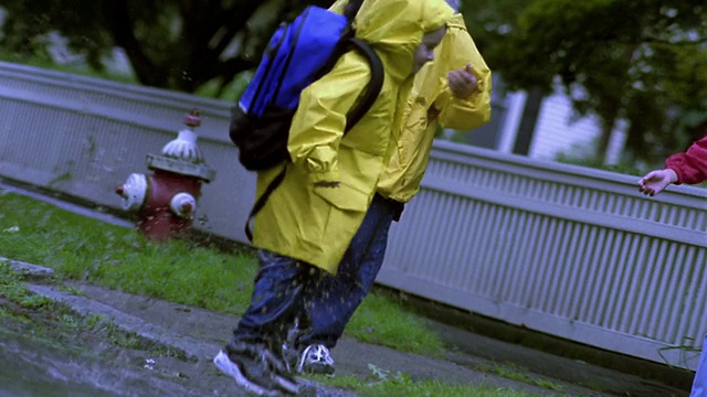 CANTED PAN小男孩在水坑里跑+跳，年长的男孩和女孩在看视频素材