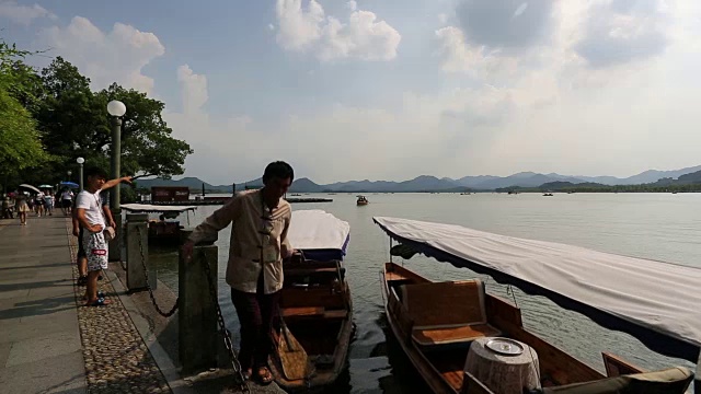 一名男子在中国杭州西湖的岸边拉着一条船视频素材