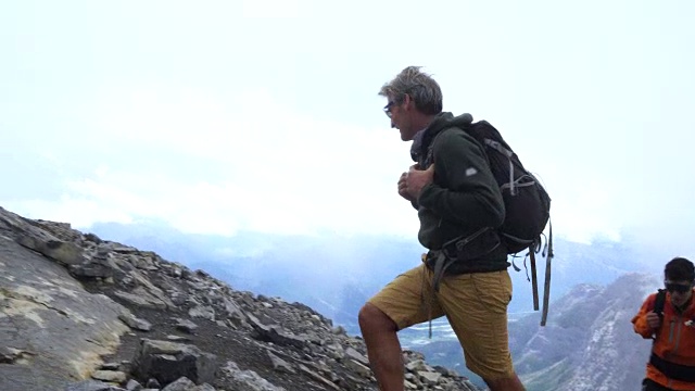 成熟和年轻的登山家攀登山脊，雾天视频素材