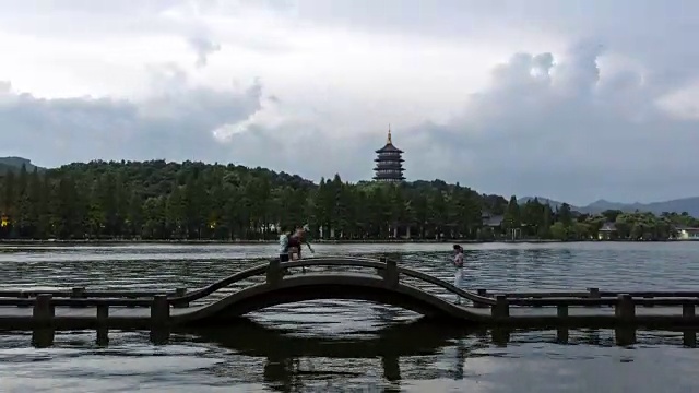 从白天到夜晚4K延时:游客沿着石桥走在雷峰塔上，杭州，中国视频素材