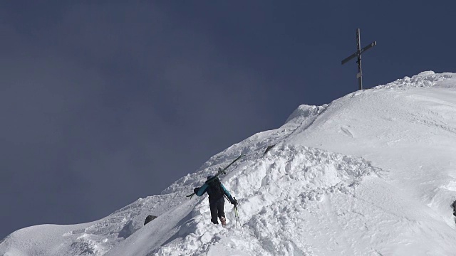 一个人带着滑雪板在冬天登上山顶视频素材