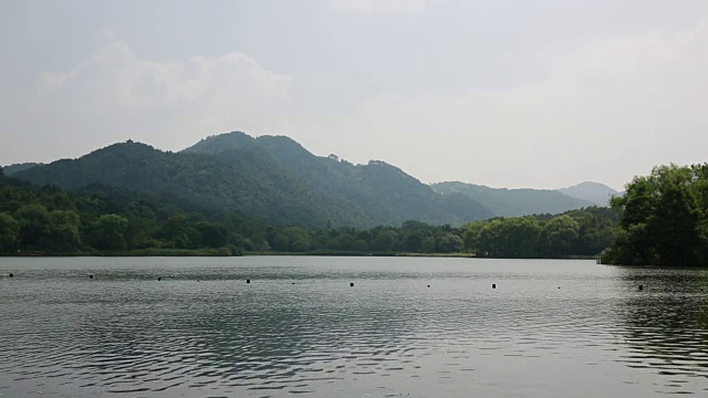 中国杭州，一艘小船在绵延的青山上的西湖上航行视频素材