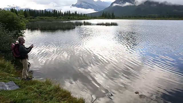 徒步者下到山上的湖泊，用智能手机拍摄视频视频素材