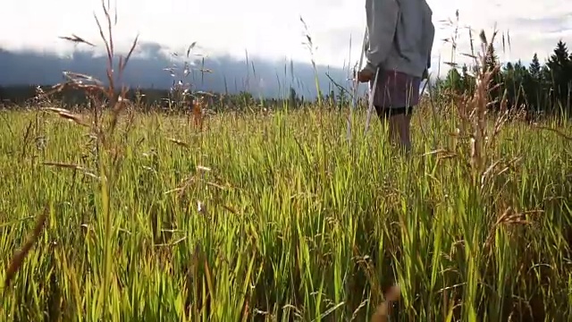 女人拄着拐杖走进草地，望着群山视频素材