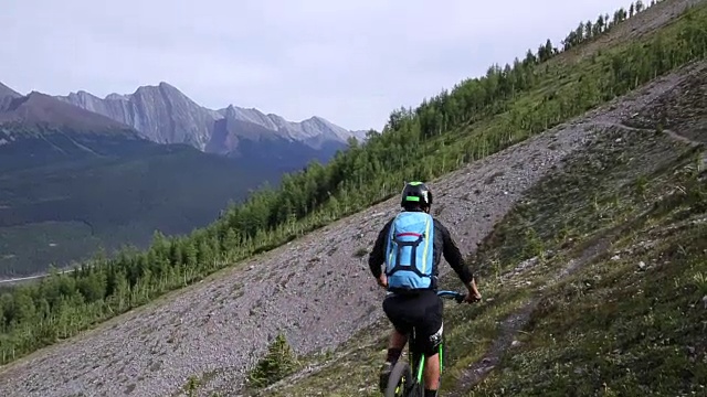 骑山地车的人沿着一条狭窄的小径向山脊行进视频素材